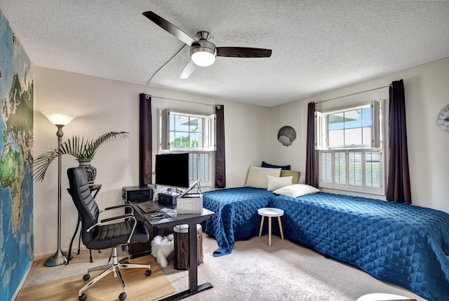 bedroom featuring a textured ceiling, carpet flooring, multiple windows, and ceiling fan