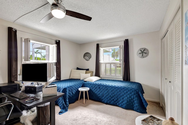 carpeted bedroom featuring a closet, ceiling fan, and a textured ceiling