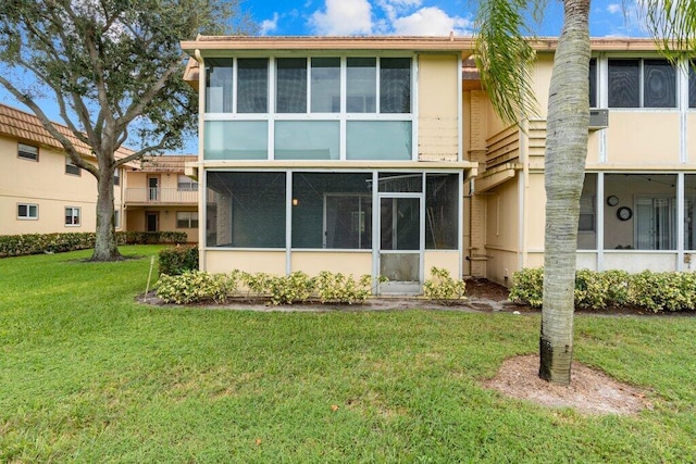 back of property with a sunroom and a lawn