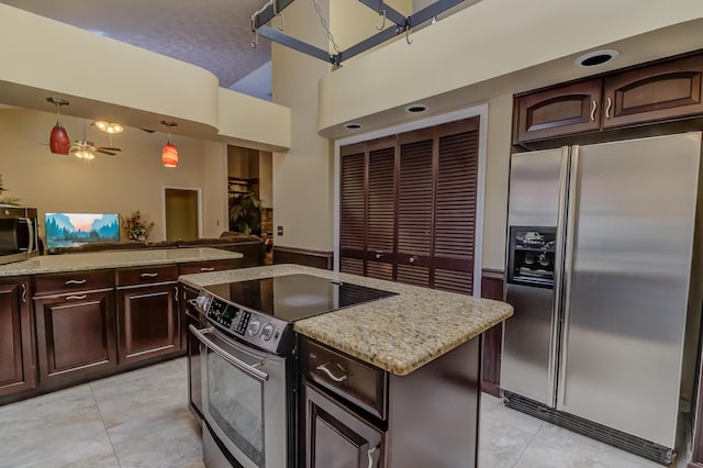 1138 SW Greenbriar Cv, Port Saint Lucie, FL 34986 - kitchen with stainless steel appliances, light tile patterned floors, decorative light fixtures, dark brown cabinetry, and light stone countertops