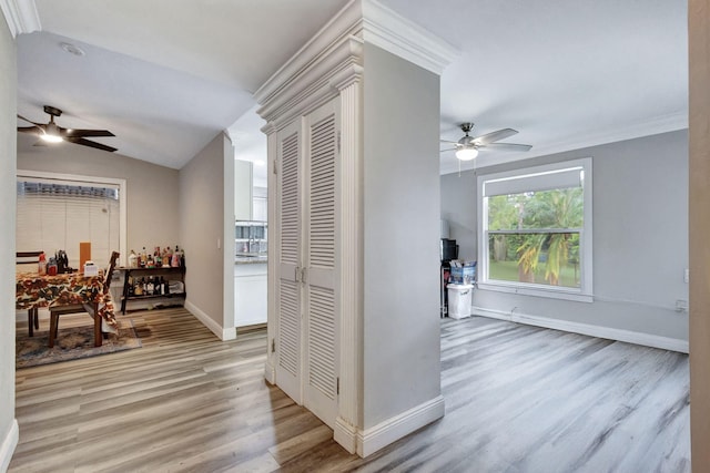 corridor with light hardwood / wood-style floors, lofted ceiling, and crown molding