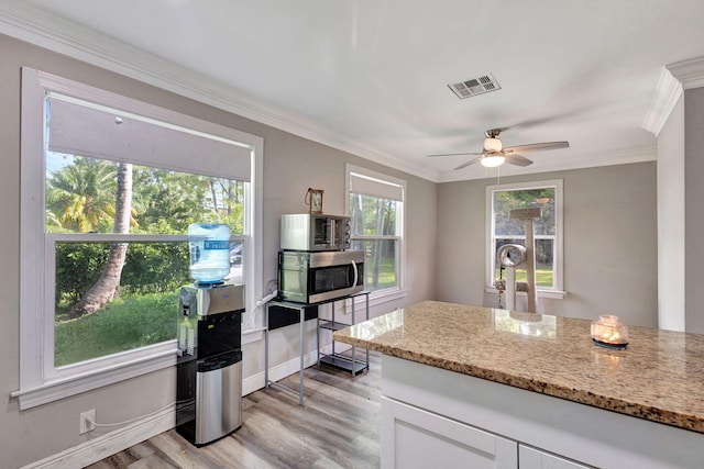 kitchen featuring light hardwood / wood-style floors, ornamental molding, light stone countertops, ceiling fan, and white cabinets