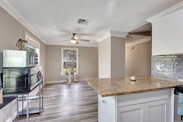 kitchen featuring light stone countertops, white cabinetry, light hardwood / wood-style floors, and ornamental molding