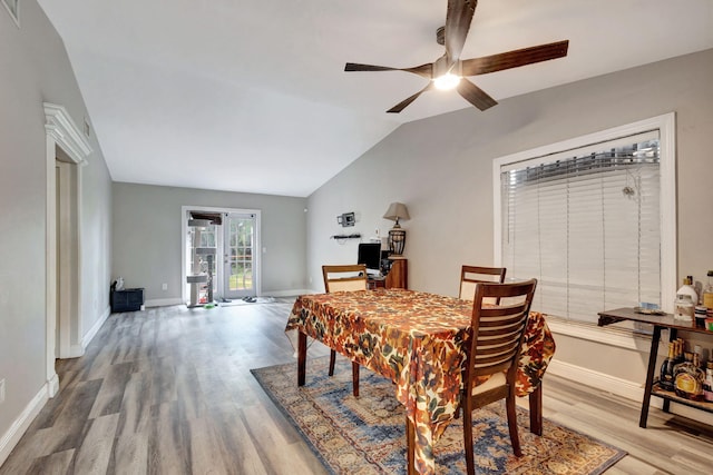 dining space with light hardwood / wood-style floors, ceiling fan, and vaulted ceiling