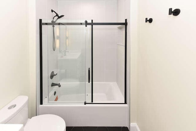 bathroom featuring bath / shower combo with glass door and toilet