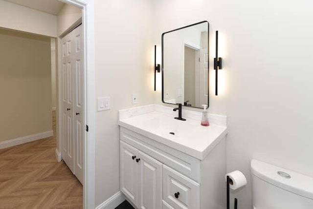 bathroom featuring vanity, toilet, and parquet floors