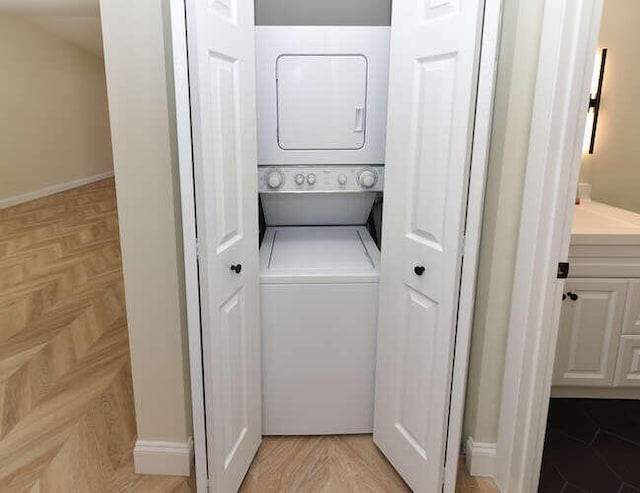 clothes washing area with light parquet floors and stacked washing maching and dryer