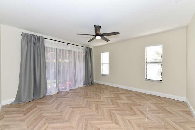 spare room featuring ceiling fan, a healthy amount of sunlight, and light parquet floors