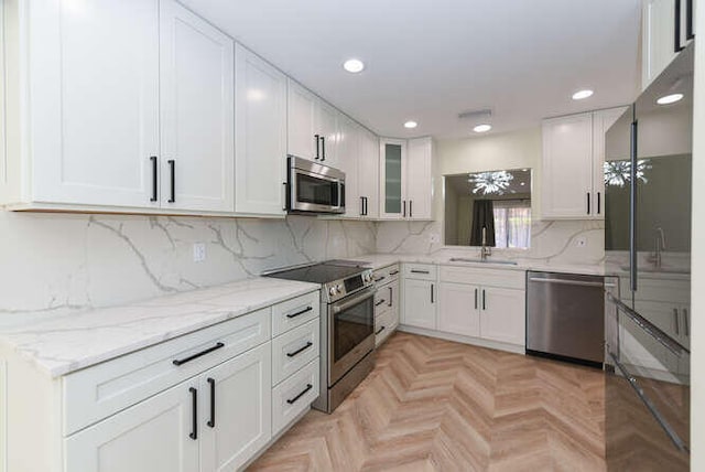 kitchen featuring stainless steel appliances, white cabinets, tasteful backsplash, and light parquet floors