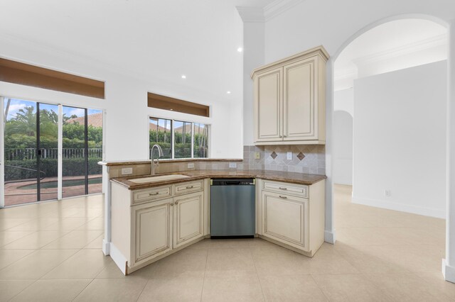 kitchen with cream cabinetry, backsplash, sink, light tile patterned floors, and stainless steel dishwasher