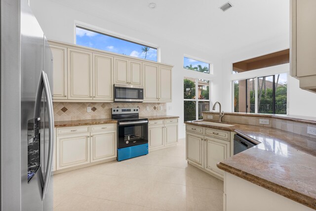 kitchen featuring light tile patterned floors, stainless steel appliances, sink, and cream cabinetry