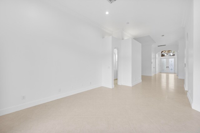 unfurnished living room featuring french doors, crown molding, and light tile patterned floors