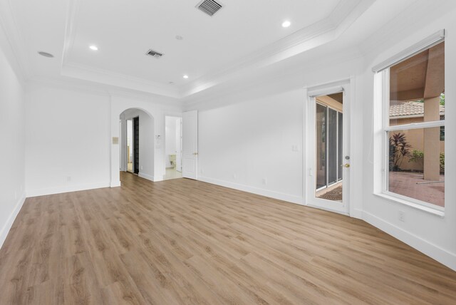 unfurnished living room with light hardwood / wood-style floors, ornamental molding, and a tray ceiling