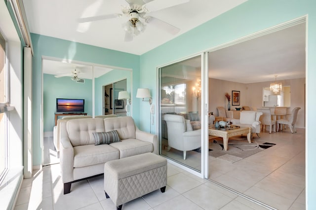 living room featuring ceiling fan with notable chandelier and light tile patterned floors