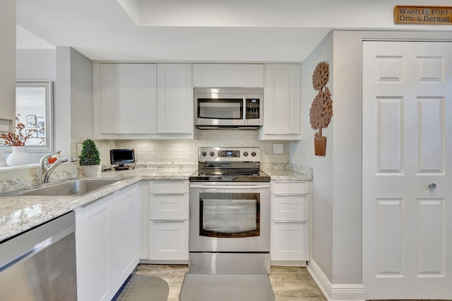 kitchen featuring light stone countertops, sink, appliances with stainless steel finishes, and white cabinetry