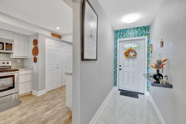 foyer with light hardwood / wood-style floors, a textured ceiling, and plenty of natural light