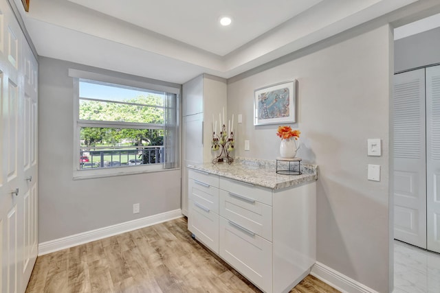 interior space with white cabinets, light stone counters, and light wood-type flooring