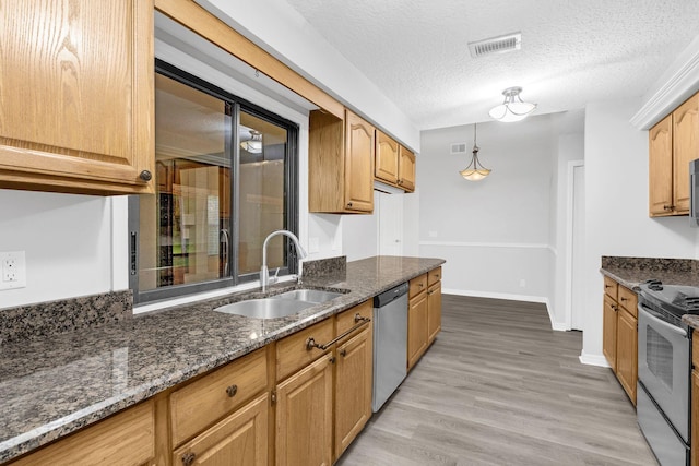 kitchen featuring hanging light fixtures, sink, a textured ceiling, stainless steel appliances, and light hardwood / wood-style floors