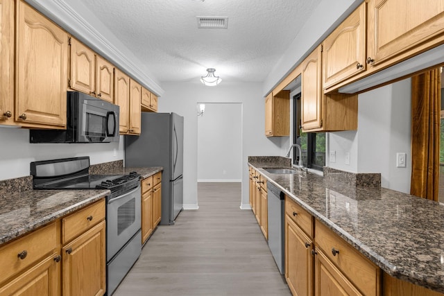 kitchen featuring stainless steel appliances, sink, light wood-type flooring, and a textured ceiling