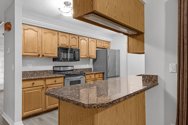 kitchen featuring dark stone countertops, kitchen peninsula, light hardwood / wood-style flooring, appliances with stainless steel finishes, and a textured ceiling