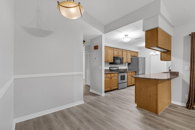 kitchen featuring stainless steel appliances, light wood-type flooring, and a textured ceiling