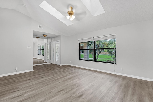 unfurnished living room featuring hardwood / wood-style flooring, a wealth of natural light, and lofted ceiling with skylight