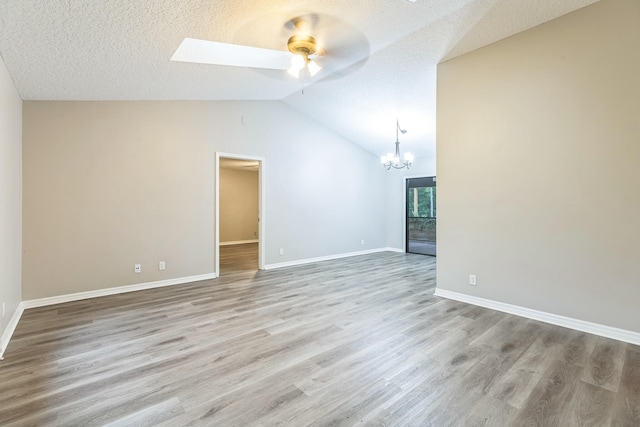 unfurnished living room featuring ceiling fan with notable chandelier, a textured ceiling, light wood-type flooring, and lofted ceiling with skylight