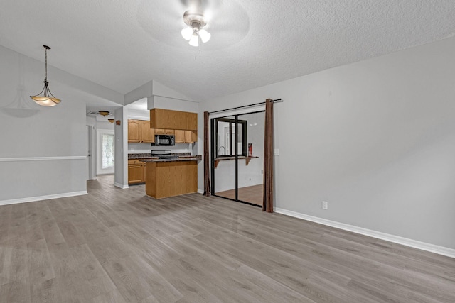 kitchen featuring light hardwood / wood-style floors, ceiling fan, decorative light fixtures, lofted ceiling, and a textured ceiling