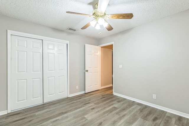 unfurnished bedroom with ceiling fan, a textured ceiling, light hardwood / wood-style flooring, and a closet