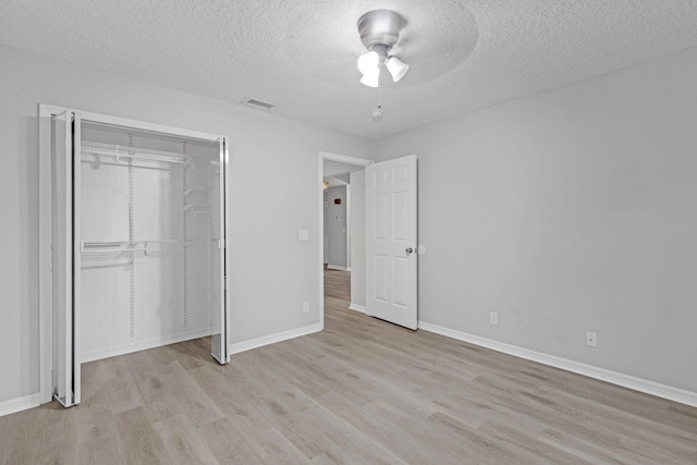 unfurnished bedroom with a closet, light hardwood / wood-style flooring, a textured ceiling, and ceiling fan