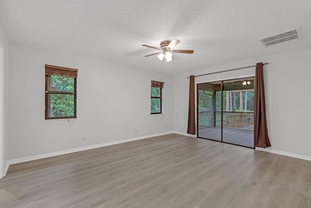 spare room with a textured ceiling, ceiling fan, and light hardwood / wood-style flooring