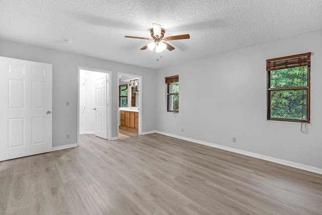 unfurnished bedroom featuring ceiling fan, ensuite bath, light hardwood / wood-style floors, and multiple windows