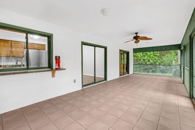 unfurnished sunroom with ceiling fan and sink