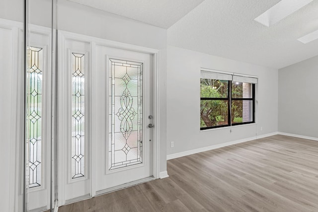 foyer entrance with a skylight, light wood-type flooring, and a textured ceiling