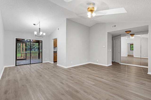 unfurnished living room with ceiling fan with notable chandelier, light wood-type flooring, and lofted ceiling with skylight