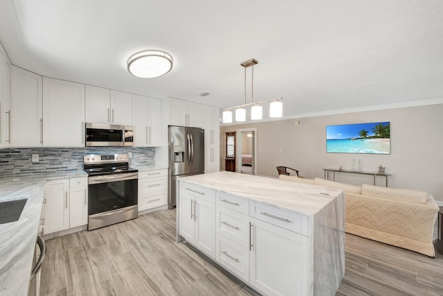 kitchen featuring light hardwood / wood-style floors, appliances with stainless steel finishes, hanging light fixtures, crown molding, and white cabinets