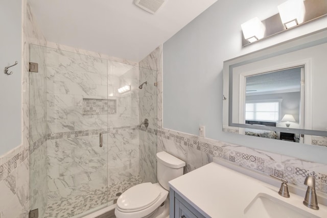 bathroom with vanity, toilet, an enclosed shower, and tile walls