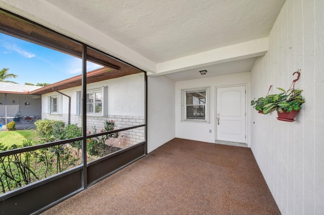 unfurnished sunroom featuring beam ceiling