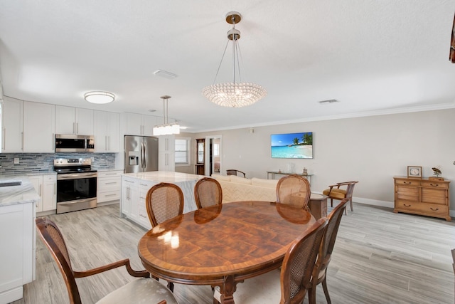 dining area with light hardwood / wood-style flooring, a notable chandelier, and crown molding