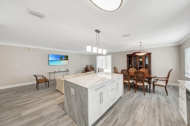 kitchen with ornamental molding, white cabinetry, decorative light fixtures, light hardwood / wood-style floors, and a center island