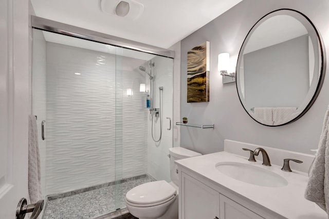 bathroom with vanity, a shower with shower door, and toilet