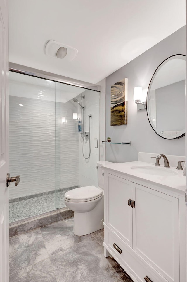 bathroom featuring vanity, toilet, and a shower with shower door