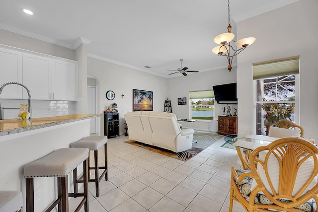 living room featuring light tile patterned floors, ceiling fan with notable chandelier, crown molding, and sink