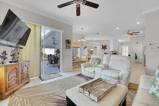 living room featuring light tile patterned flooring, ceiling fan with notable chandelier, and ornamental molding