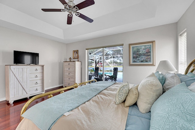 bedroom with hardwood / wood-style floors, ceiling fan, a raised ceiling, and access to outside