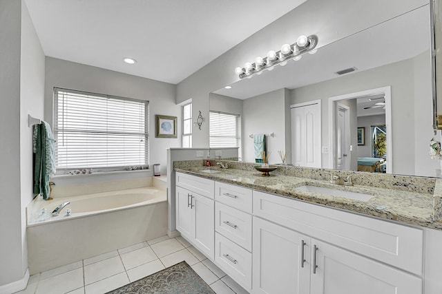 bathroom with tile patterned floors, a bath, vanity, and a healthy amount of sunlight