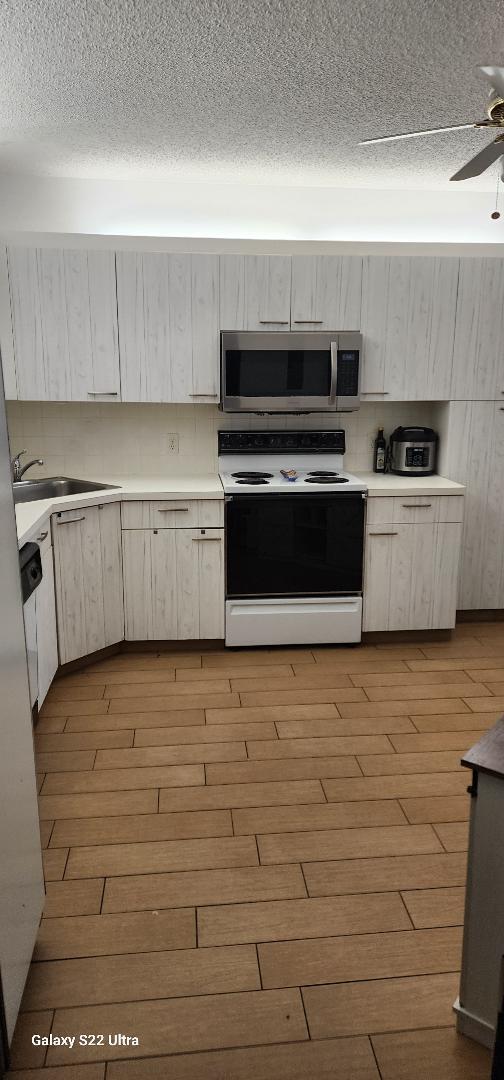 kitchen featuring electric range, ceiling fan, sink, and light hardwood / wood-style flooring