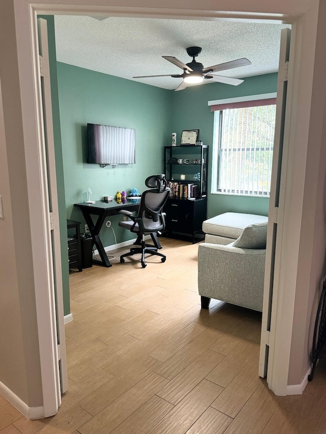 office space with ceiling fan, light wood-type flooring, and a textured ceiling