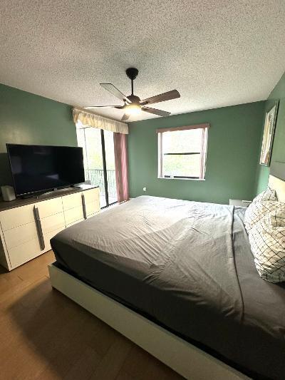 bedroom with a textured ceiling, hardwood / wood-style flooring, and ceiling fan