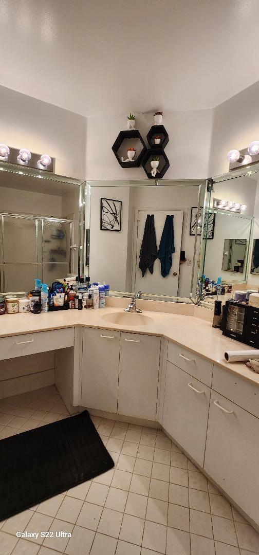 bathroom featuring a shower with door, vanity, and tile patterned flooring